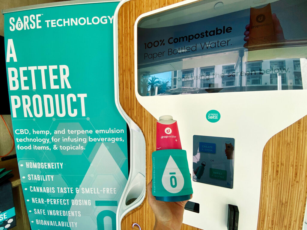 Person holding a drink bottle in front of DropWater kiosk